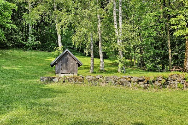 Studánka a venkovní sezení pod stromy.